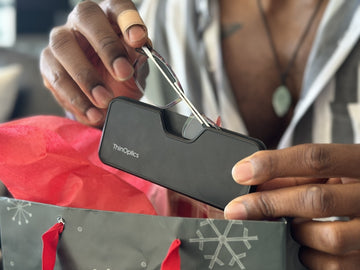 A pair of hands taking out a MagSafe® Connect Case with Brooklyn Blue Light Blockers from a holiday gift bag.